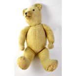 A mid-20th century jointed teddy bear with humped back and blonde fur, stitched nose,