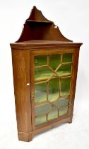 A mahogany floor standing corner cupboard with shaped upper shelf above astragal glazed door,