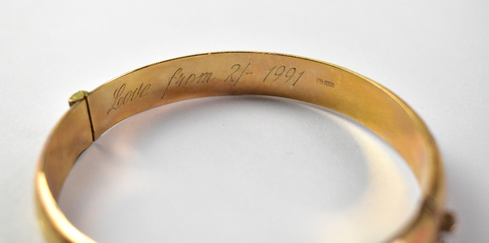 A 9ct yellow gold bangle with chased scroll decoration and safety chain, approx 11.5g. - Image 4 of 4