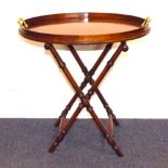 A mahogany oval tray with raised brass handles on mahogany faux bamboo stand, 55 x 55 cm.