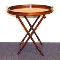 A mahogany oval tray with raised brass handles on mahogany faux bamboo stand, 55 x 55 cm.