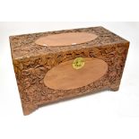 A camphor wood carved blanket box profusely decorated with flowers and fruit, on bracket feet,