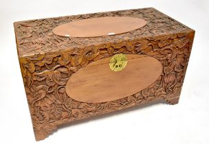 A camphor wood carved blanket box profusely decorated with flowers and fruit, on bracket feet,