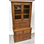 ERCOL; an oak wall unit comprising moulded cornice above pair of glazed doors with bevelled glass,