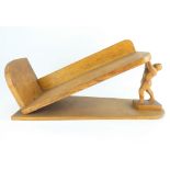 An unusual Arts & Crafts style handmade elevated oak book rack modelled as an athletic man on base,