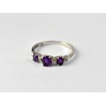 A 9ct white gold ladies' dress ring set with three graduating oval amethysts and small diamond