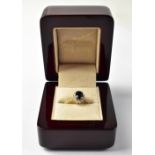 An 18ct gold ring set with central claw set sapphire in a halo of tiny claw set brilliant cut