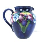 WALTER MOORCROFT; a large jug with 'Clematis' pattern on blue ground,