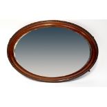 A 1930s mahogany oval wall mirror with beaded border and bevelled glass, 73 x 102cm.