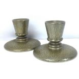 TUDRIC PEWTER; a pair of hammered pewter short candlesticks, stamped 'Tudric Pewter 01761' to base,