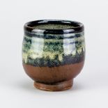 TREVOR CORSER (1938-2015) for Leach Pottery; a stoneware yunomi covered in tenmoku, kaki and nuka