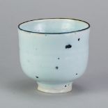 EMMANUEL COOPER (1938-2012); a porcelain teabowl covered in pale blue glaze with bronze rim and