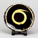 DYLAN BOWEN (born 1967); a slipware plate covered in chestnut glaze with yellow trailed