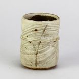 MIKE DODD (born 1943); a stoneware brush pot covered in pale green ash glaze with incised
