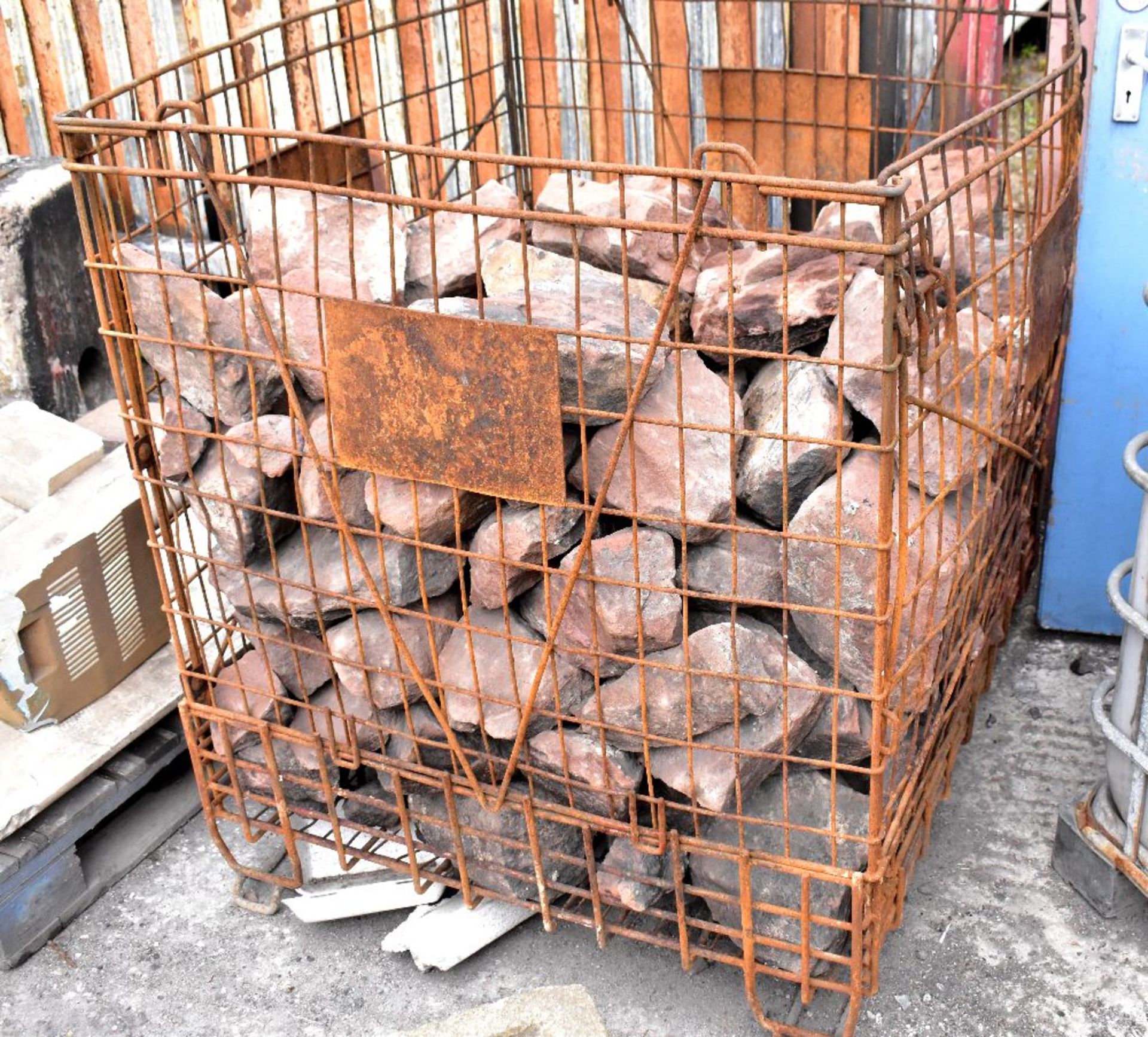 A cage containing a quantity of various sized rocks (mostly sandstone).