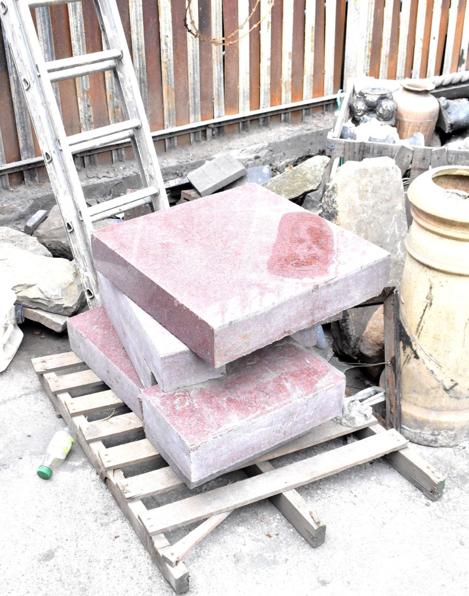 A pallet containing a small quantity of various size red granite slabs,