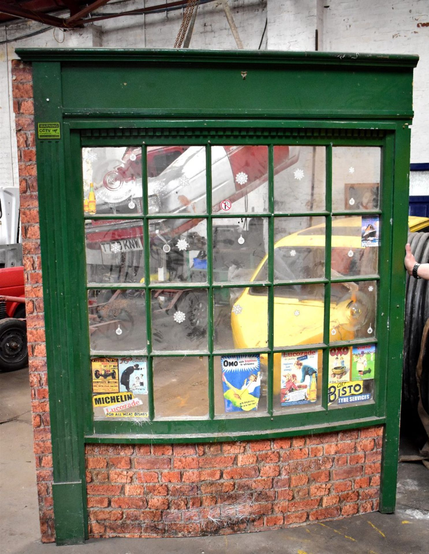 A prop of a bow-fronted shop front, with various advertising stickers in the windows, height 224cm,