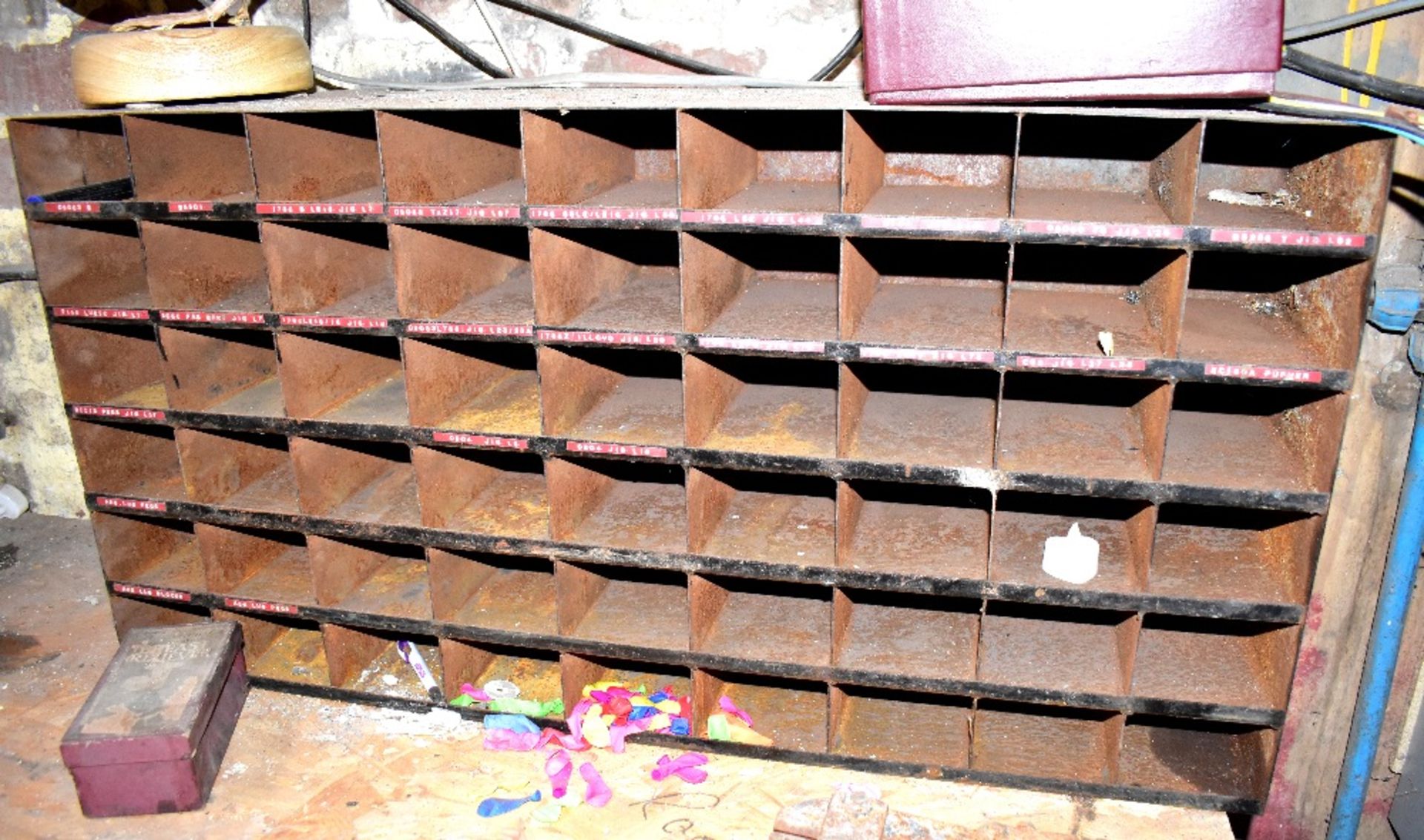 A bank of metal pigeonholes with various stock labels attached.