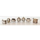 An Indian white metal four piece cruet with cast scrolling detail, a novelty pepperette in the