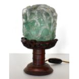 A 20th century Chinese jade style glass shade on turned wooden stand with floral decoration,