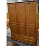 A contemporary pine three-door wardrobe with drawers to the base, height 185cm, width 128cm.