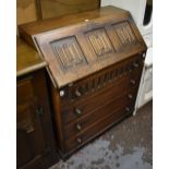 A mid-20th century oak bureau with linenfold decoration to the fall front and four long drawers,