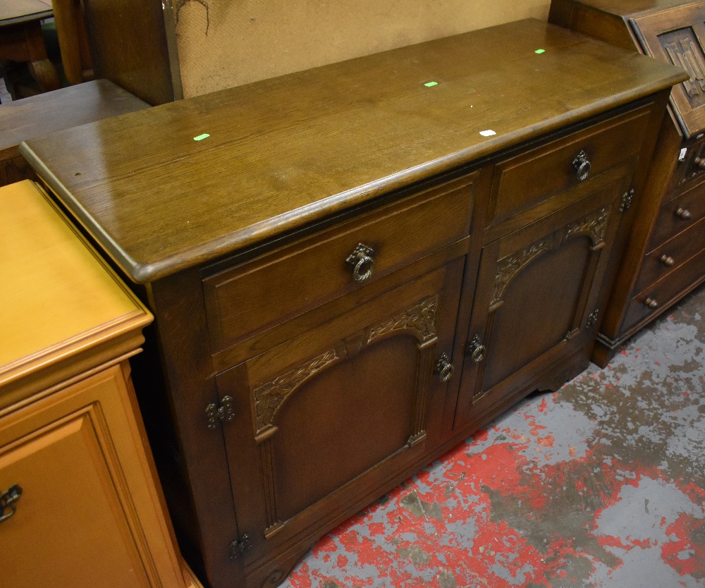 A reproduction oak dresser base with two drawers above two arched panelled cupboard doors,