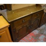 A reproduction oak dresser base with two drawers above two arched panelled cupboard doors,