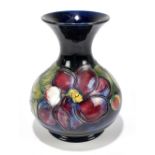 WALTER MOORCROFT; a baluster shaped vase decorated in the 'Clematis' pattern on a blue ground,