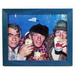 K. DUMAS; a coloured photograph depicting three gentleman drinking can of Amstel beer, inscribed