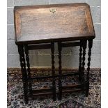 An early 20th century oak bureau, the fall front supported in an unusual fashion by two gateleg
