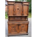 A 19th century carved oak Flemish cabinet, the upper section with three panelled doors, the