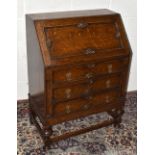 An early 20th century oak bureau with mechanical fall front enclosing fitted interior above three