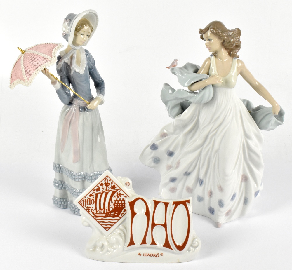 LLADRO; two figures comprising a maiden wearing a bonnet hat and holding a parasol, height 32cm, and