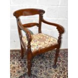 An early Victorian mahogany elbow chair with floral drop-in seat, on turned column supports.