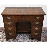 A George III style walnut knee-hole desk, with an arrangement of seven drawers, on bracket feet,