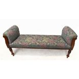 A late Victorian carved walnut window seat upholstered in a later floral material, on turned