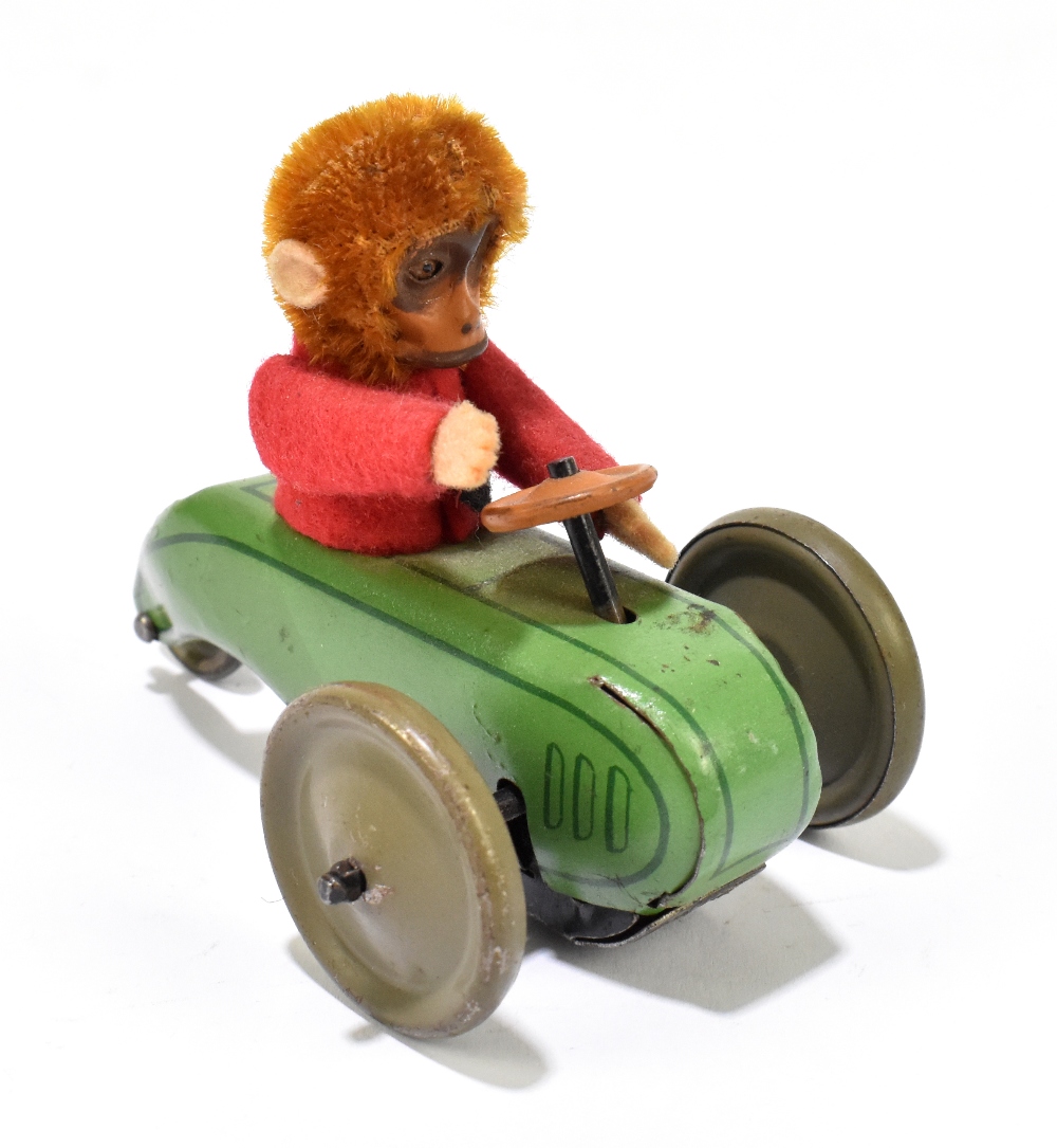 SCHUCO; a tinplate friction model of a three wheel motorcar with monkey driver, length 9cm.