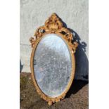 Gilt framed oval mirror with scroll detail.