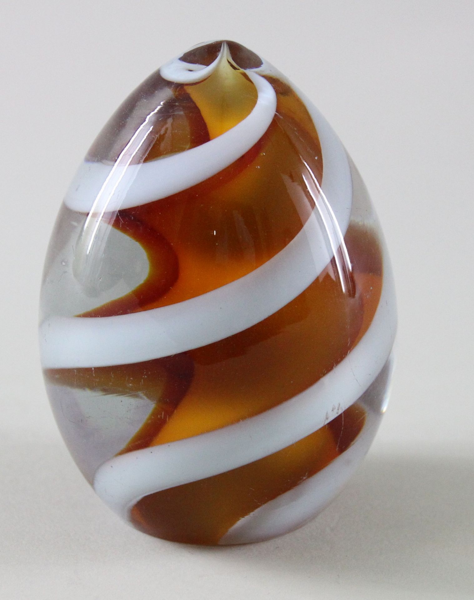 Paperweight, Eiform, 20. Jhd. Orangefarbenes Glas, mittig Wirbel durch eine weiße Spirale