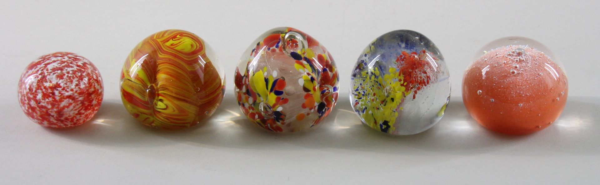 5 kleine Paperweights, 20. Jhd. Kugelige Form, Klarglas, Farbspiele in Orange, Rot und Gelb,