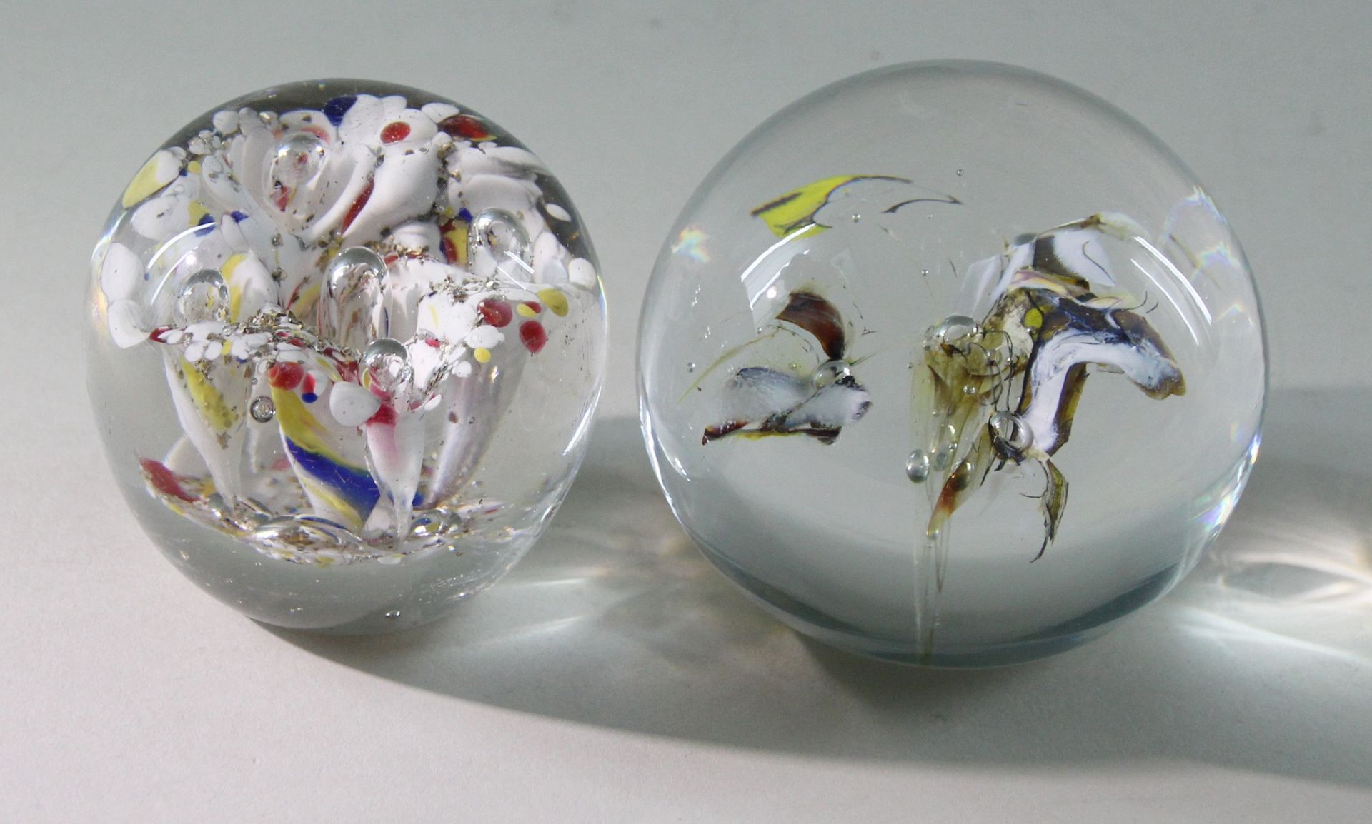 2 Paperweights, "Blüte", 20. Jhd. Kugelige Form, Klarglas, mittig Blüten in überwiegend weißer