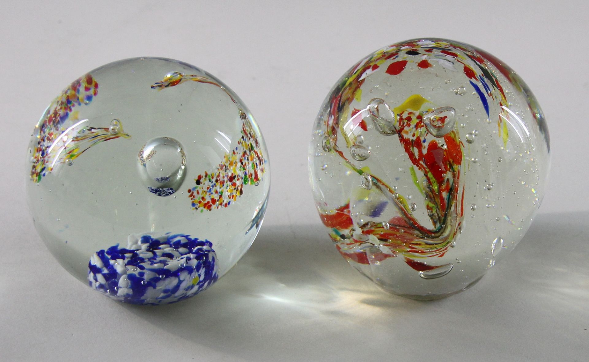 2 Paperweights, 20. Jhd. Kugelige Form, Klarglas, polychromer Farbwirbel mit Luftblasen, 1 x auf