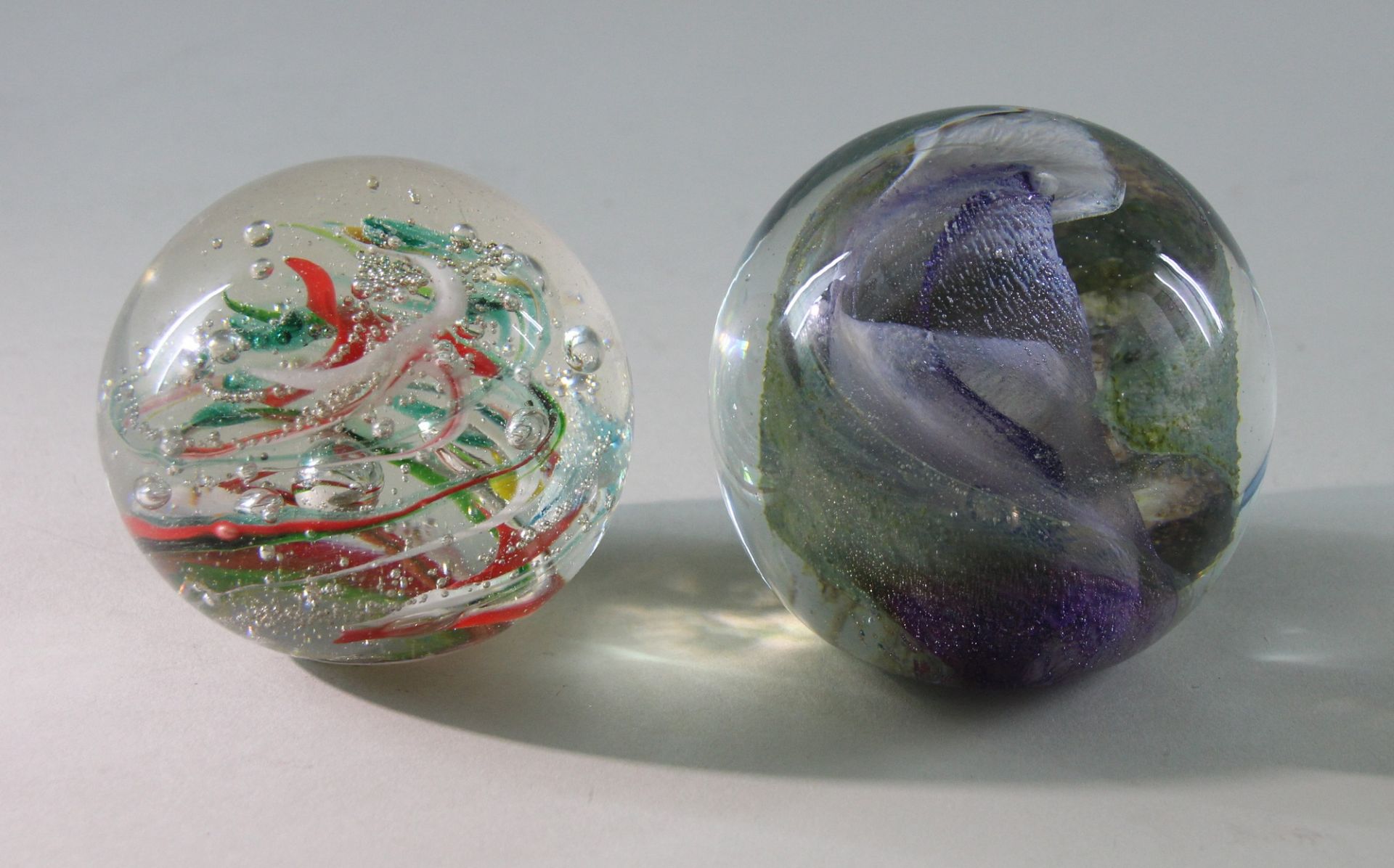 2 Paperweights, "Spiralwirbel", 20. Jhd. Kugelige Form, Klarglas, 1 x zentraler Wirbel in Violett,