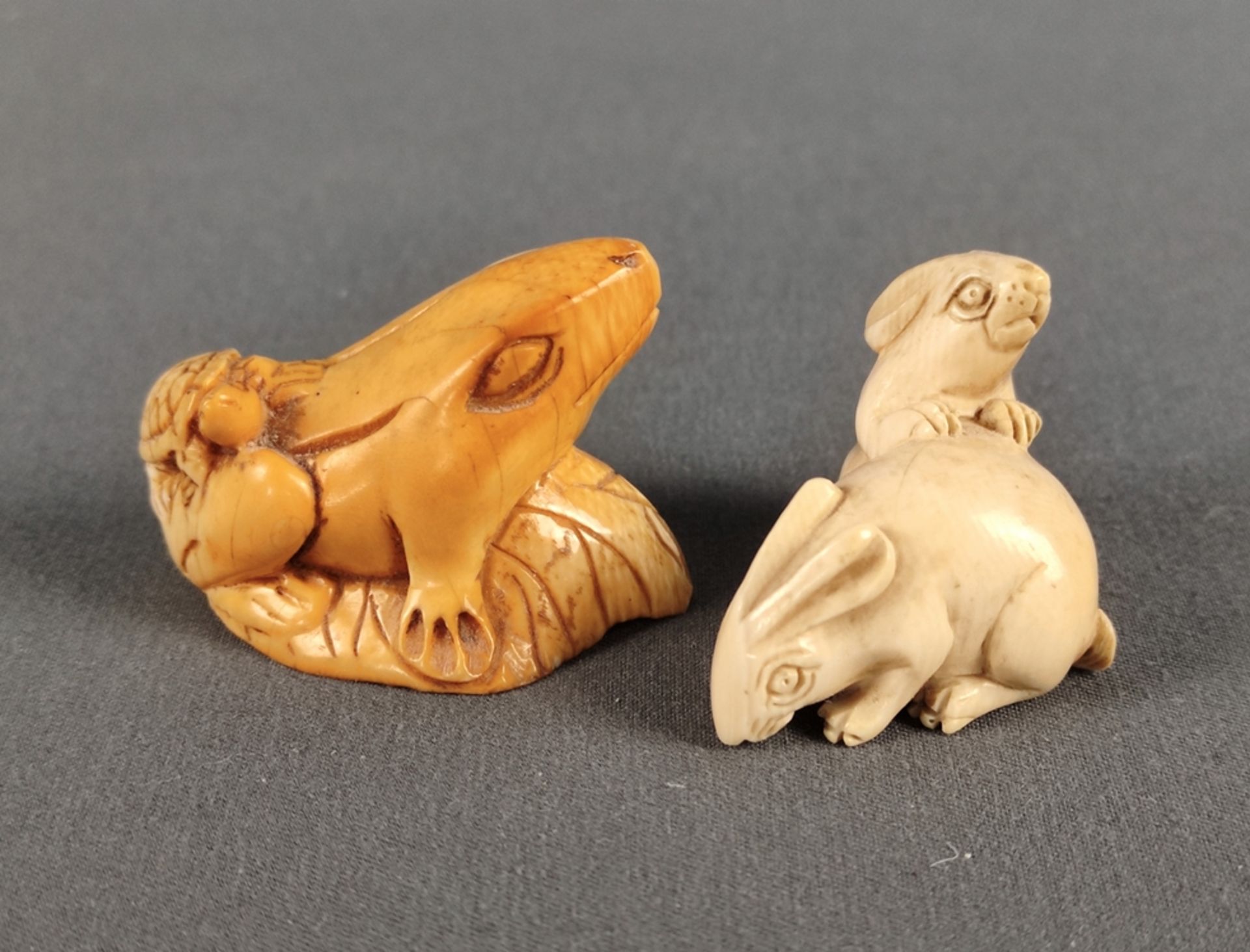 Zwei Netsuke, einmal mit zwei Hasen, Maße ca. 27x40x24mm und eine mit Kröte und Schildkröte, Maße c