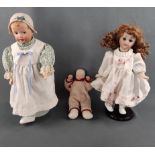 Drei Puppen, eine im geblümten Kleid und weißen Schuhen, Kopf aus Biskuit-Porzellan, ebenso wie der