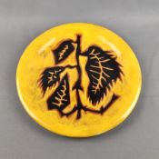 Zierteller, Keramik, abgebildet ist ein Zweig mit vier Blättern in schwarz auf ockerfarbenem Grund,