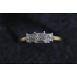 A three stone Princess cut diamond ring set in 18ct yellow gold