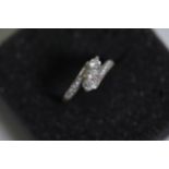 A 3 stone diamond cross over ring with diamond shoulders
