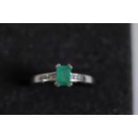 An emerald solitaire ring with diamond shoulders set in 9ct white gold